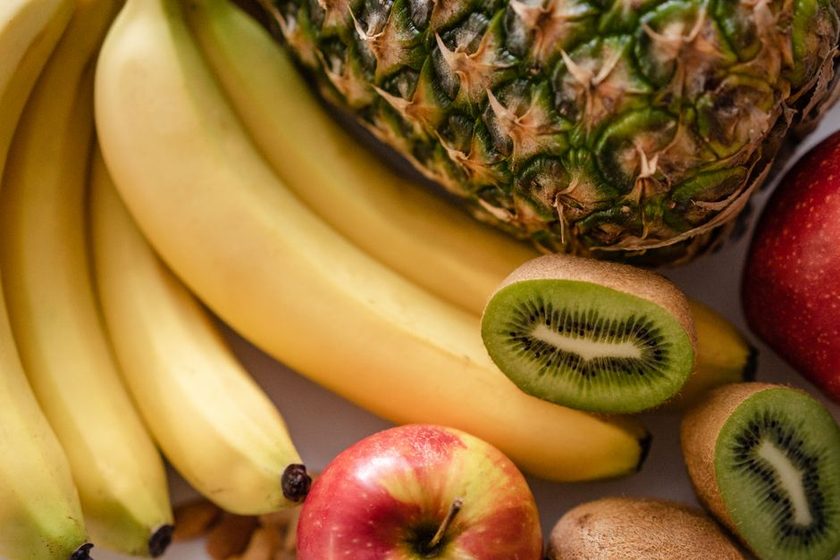 Fatias frescas de abacaxi e kiwi cortadas sobre tábua de madeira clara