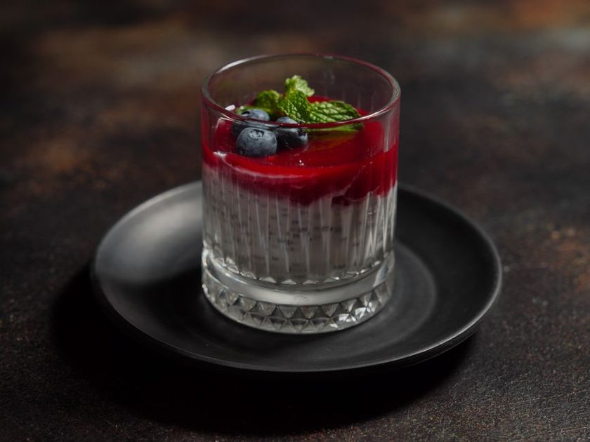 Copo de vidro com sobremesa gelada de camadas, cobertura de frutas vermelhas, mirtilos e hortelã