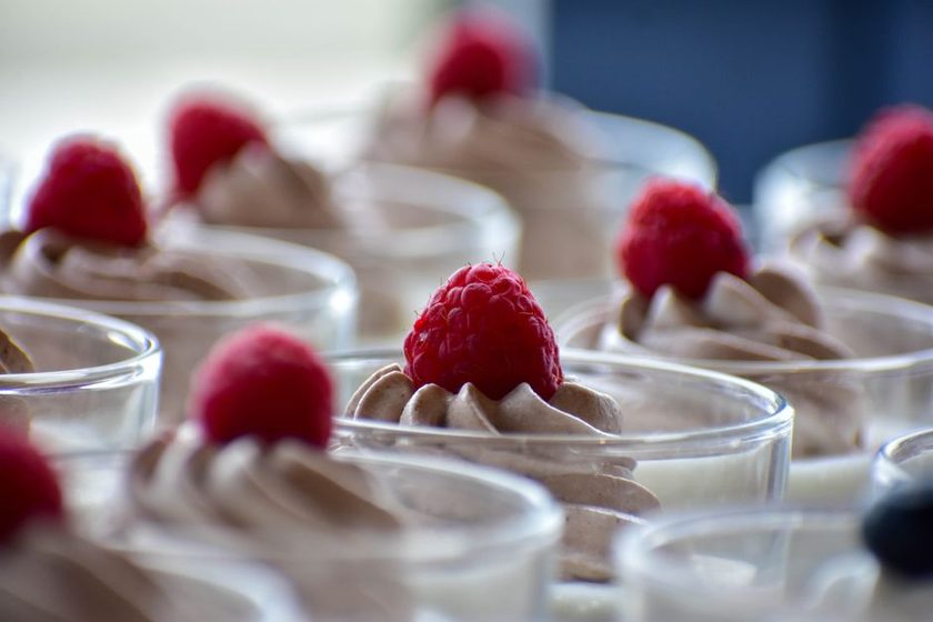 Taça com mousse rosa de frutas vermelhas decorada com frutas frescas inteiras